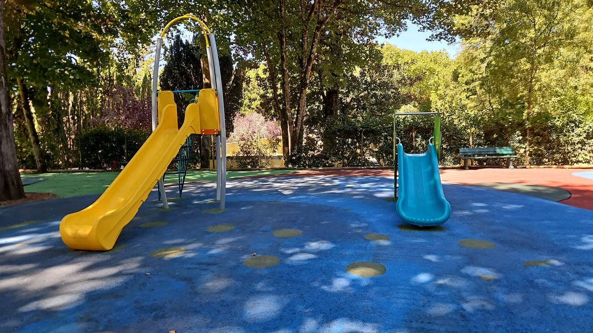 O parque infantil do Jardim do Cerco depois da substituição de 2026: dois escorregas pequenos sobre pavimento de borracha liso.
