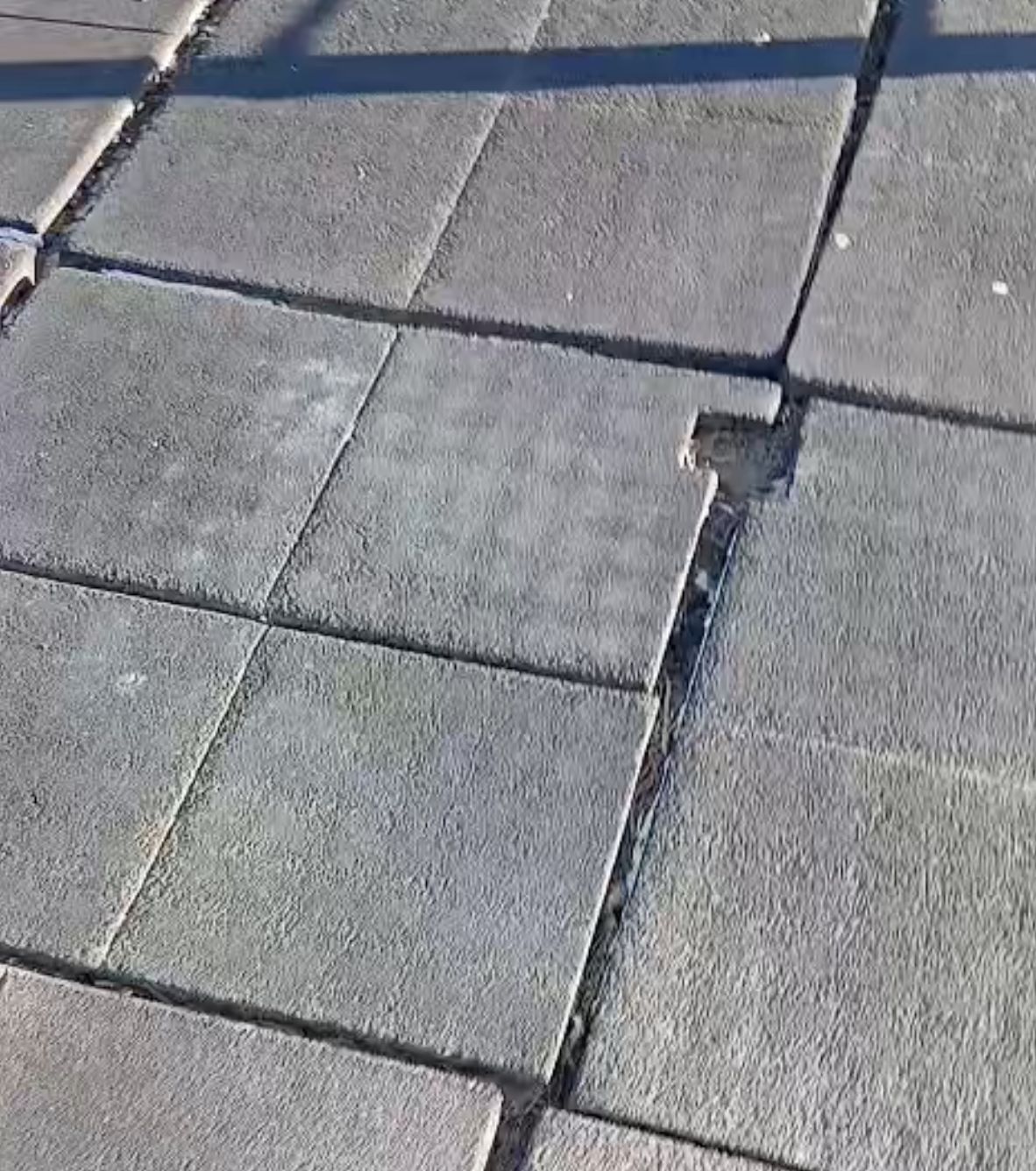 Placas de pavimento amortecedor degradadas e fissuradas, com juntas abertas.