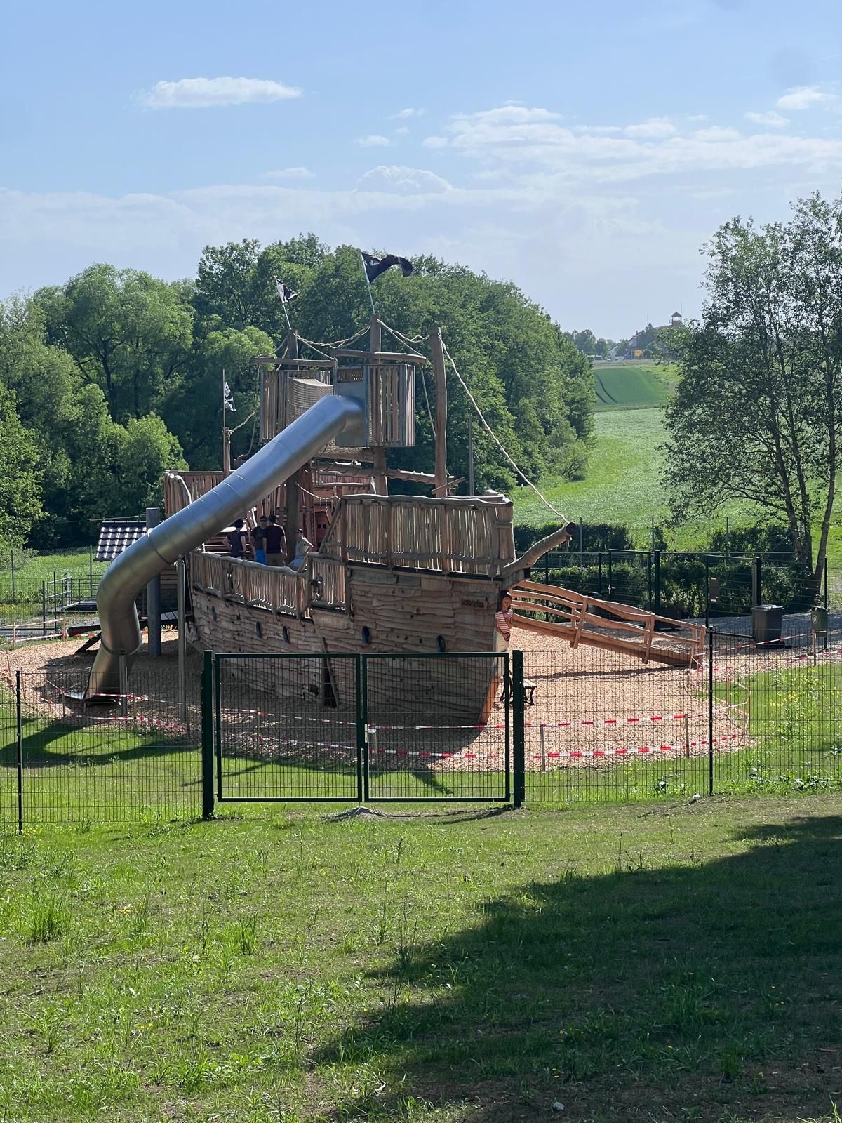 Navio de madeira de grande dimensão num parque infantil, com escorrega tubular.